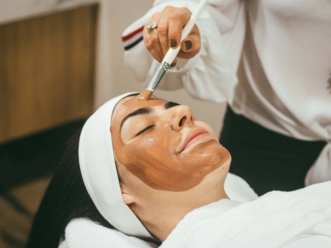 Esteticista aplicando máscara facial numa cliente da Essenza