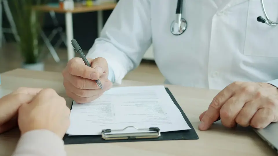 Mãos de médico preenchendo uma ficha na prancheta