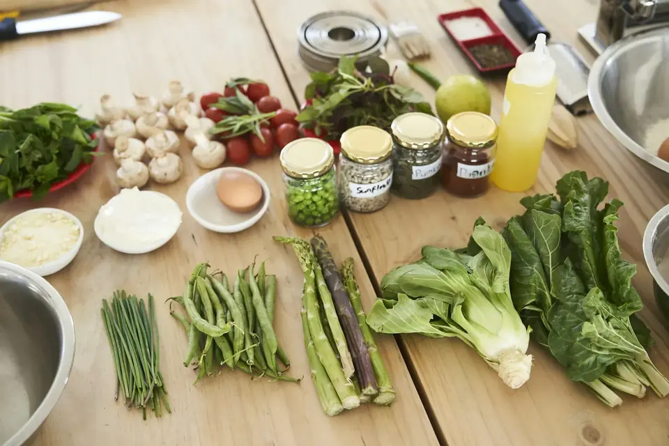 Mesa de madeira com verduras, legumes e potes de temperos