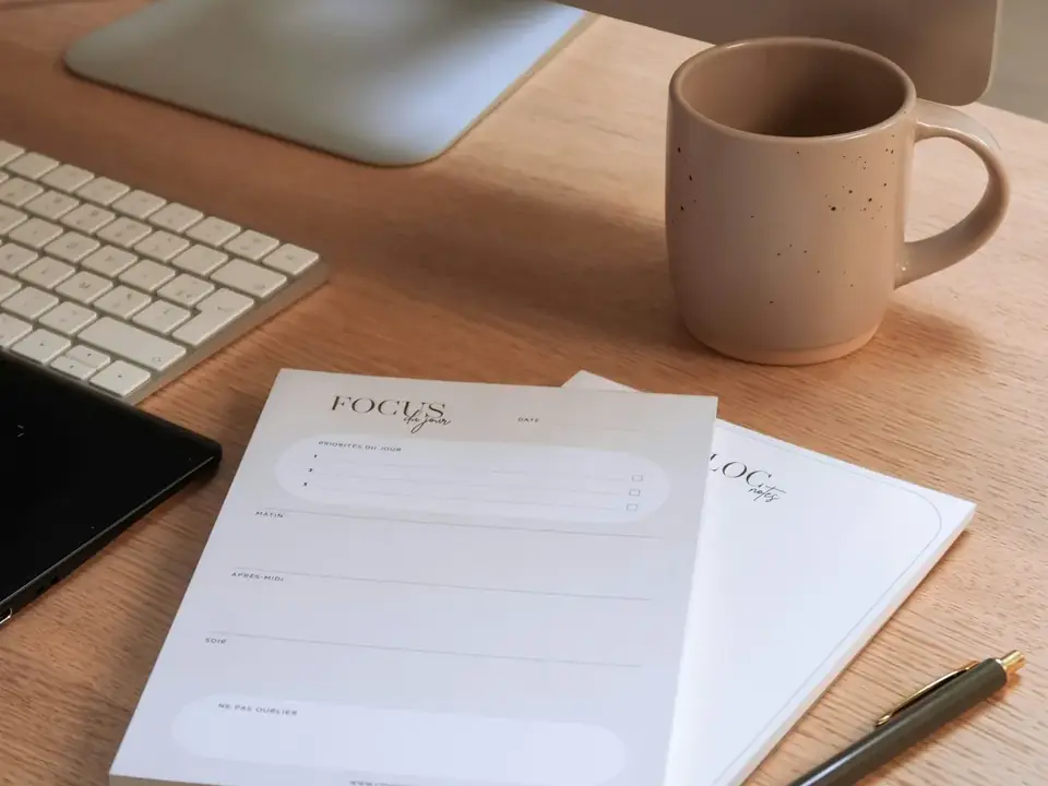 Mesa de trabalho com caderno de anotações e xícara