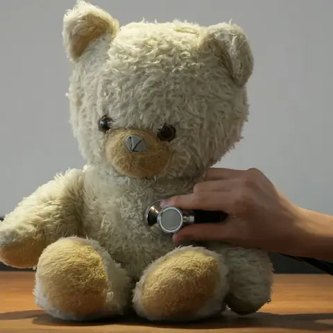 Mão com estetoscópio no peito de um ursinho de pelúcia
